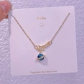 Dettaglio ravvicinato di una collana dorata a forma di pianeta con stella e ciondolo blu orbitale - Anello del Pianeta Meteora (XK0048)