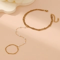 Detail eines mehrlagigen Goldarmbands mit weißen Perlen und Ringkette auf rosa Grund - Gold Handkette Stil A (Perlendekor)