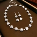 Detalle de un conjunto de joyas de flores plateadas con brillantes de imitación y collar - Conjunto de 2 Piezas Flor Plateada (Pendientes de Botón + Collar)