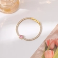 Close-up of golden bracelet featuring a pink oval gemstone and rectangular zircons - Gold Oval Style