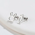 Macro shot of silver asymmetrical rabbit and carrot studs on a white geometric surface - Silver