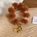 Primer plano de pulsera de cuentas con pompón marrón y colgante floral dorado - Colgante de Flor / Marrón