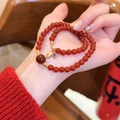 Detailansicht eines roten Achat-Perlenarmbands mit goldenem 'Fu'-Anhänger am Handgelenk. - Doppelschleife Glücksstil (13#)