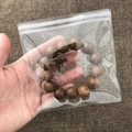 Transparent PVC anti-oxidation jewelry bag containing a brown wooden beaded bracelet - 100 Pieces / 12*12cm (26 Microns)