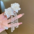 Detail van witte bloem oorbellen met parelkwastjes en gouden afwerking in de hand - 41# Witte 3D Bloem