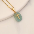 Detailed shot of a turquoise gemstone pendant with an inlaid golden cross on a chain - Green Aventurine
