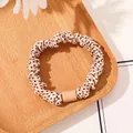 Close-up of leopard print scrunchie with matte bead detail on a wooden tray with flowers - Satin Polka Dot Beige