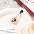 Detalle de una pinza para el pelo de acrílico con forma de guitarra en un plato decorativo - Beige