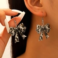 Close-up of leopard print acrylic bow earrings worn by a model in a fashion setting - Black White Spotted Bow (03 White K DZ-916)