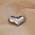 Primo piano di un ciondolo a cuore argento lucido con finitura a specchio su tessuto beige - Stile Cuore (13#)