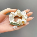 Beige satijnen scrunchie met groene strik en witte bloembedeltjes in de hand - #1 Dunne Darmcirkel Met Lelietje-van-dalenstrik - Beige