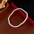 Detailed close-up of white faux pearl elastic bracelet on luxury dark brown velvet fabric - Small Shell Pearl (17.1*0.3cm)
