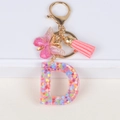 Detail of resin letter D keychain with glitter, pink tassel and butterfly charm - Letter D
