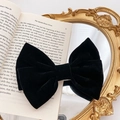 Elegant large black velvet bow hair clip placed on vintage book and mirror backdrop - Retro Velvet Style / Black Velvet Bow Clip