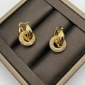 Vue macro d'un anneau doré entrelacé et de détails d'une boucle d'oreille en zircon - Doré