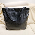 Dettaglio di una borsa tote in pelle cerata nera con tasca frontale su divano - Tipo standard / Nero