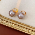Detailed shot of French vintage pearl earrings with gold hooks on a beige suede pad - Silver Earring Post - Gold - Grey