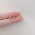 Macro shot showing size of silver crown stud earrings with sparkling stones on a finger - Hollow Crown / Silver