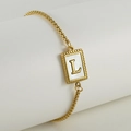 Golden titanium steel bracelet with letter L on natural shell pendant on white pillar - Letter L