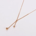 Detalle de collar de doble capa en oro rosa con pequeños colgantes de cuentas finas - Oro rosa