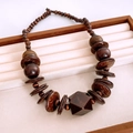 Vue détaillée de perles en bois ethniques et pendentif géométrique sur écrin en velours - Collier-Marron