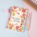 Cuaderno de espiral floral con pompón rosa sobre fondo de colores pastel suaves - Flores Coloridas