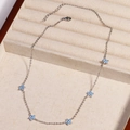 Detail view of silver chain necklace with five blue crystal flowers in a beige display box - Blue Flower - Platinum