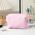 Macro detail of pink pleated makeup bag with unique wave texture and zipper closure - Pink