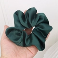Elegant dark green satin scrunchie held in hand with silky texture and smooth finish - Dark Green