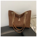 Detalle del bolso tote de ante marrón con cadena dorada y un elegante colgante de ciervo - café