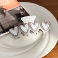 White heart hair claw clip with four gray hearts on a ceramic plate over wooden desk - Gray