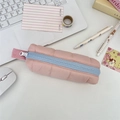 Top view of a pink quilted pencil case with blue resin zipper on a cozy desktop - Nude Pink