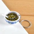 Miniature blue floral bowl keychain featuring realistic green bean soup and tiny white spoon - Mung Bean Soup