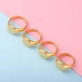 Detailed view of four polished gold oval signet rings arranged on a dual-tone background - US 9 / Gold