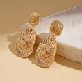 Close-up of golden geometric earrings with spiral texture and embossed teardrop design - Gold
