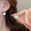 Detailed close-up of silver heart-shaped earrings with inlaid clear zircons on ear lobe - 25# Ear Buckle - Silver