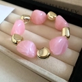 Pink resin beads and gold spheres elastic bracelet displayed on beige velvet jewelry box - Pink