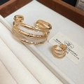 Close-up van gouden drielaagse armband met bamboetextuur en bijpassende ring - Gouden Armband Ring Set (2 stuks)