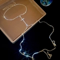 Close-up of sparkling rhinestone cross body chain with gold finish on jewelry tray - Gold