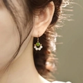 Golden drop earrings with green bead and small white pearls on model ear - Cat Claw Drop Earrings