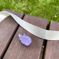 Détail d'une pince à cheveux aile violette avec strass posée sur un banc en bois - Violet