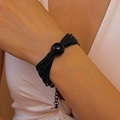 Detalle de un collar negro de varias vueltas con una gran perla pulida central puesto en el cuello - Pulsera / Negro