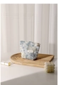 Detail of floral jacquard makeup bag with brand label on a wooden tray with candle - Small / Jacquard Tile Blue