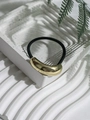 Detail eines hochelastischen schwarzen Haargummis mit poliertem goldenem Metallelement - Stil 1 (Gold Minimalistisch Bogen)