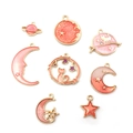 Détail de 8 breloques en émail rose avec étoiles, lune et planètes aux bords dorés - Série Rose