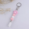 Dettaglio del portachiavi in perle di silicone rosa e bianco con fiore e nappa su fondo bianco - Rosa