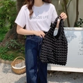 Detail of black popcorn texture on a stylish shoulder tote bag held by a model - Bubble Black