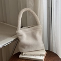 Dettaglio di borsa tote in peluche bianca soffice su libri con luce naturale - Beige