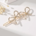 Close-up of gold hair clip with three rhinestone-encrusted bows and elegant metallic finish - Rhinestone Gold