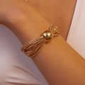 Detalle de pulsera de cadena multicapa dorada con una esfera pulida puesta en la muñeca - Pulsera / Dorado
